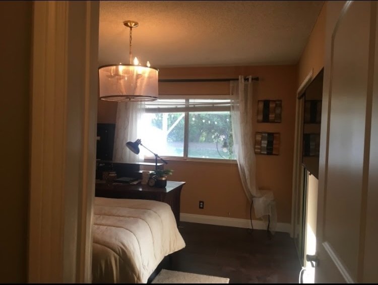 Third bedroom with pendant lamp, desk, and natural window light