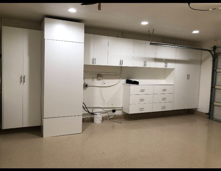 Garage with full built-in white cabinet wall and epoxy floor
