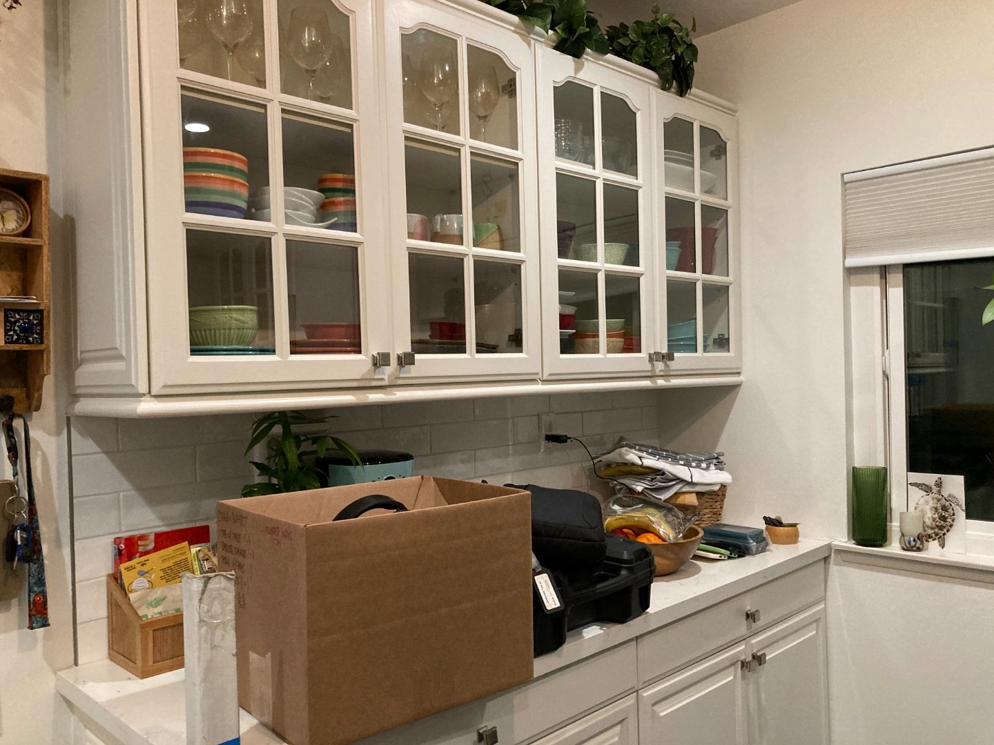 Glass-front white kitchen cabinets filled with colorful dishware