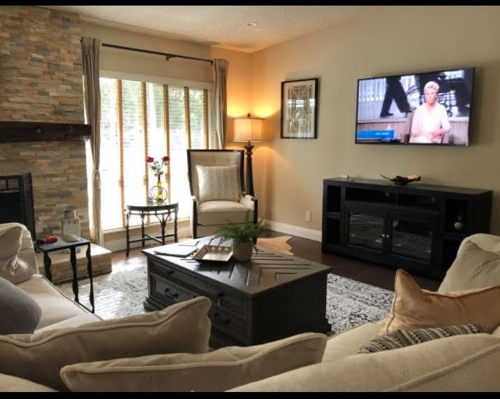 Living room seating area with stone fireplace, cream sofas, and large windows