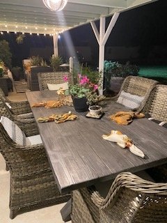 Outdoor dining table set with flowers and decor under string lights at night