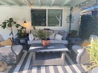 Covered patio with wicker furniture and string lights during the day