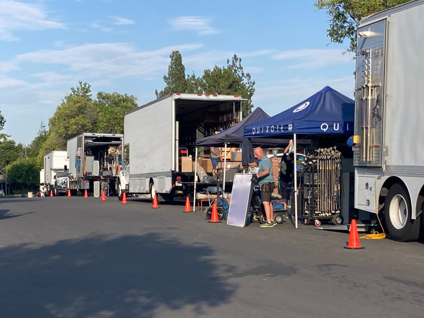 Production grip and electric trucks staged along the street with crew unloading