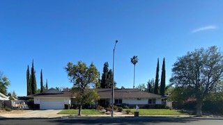 Wide neighborhood street with park visible across the road